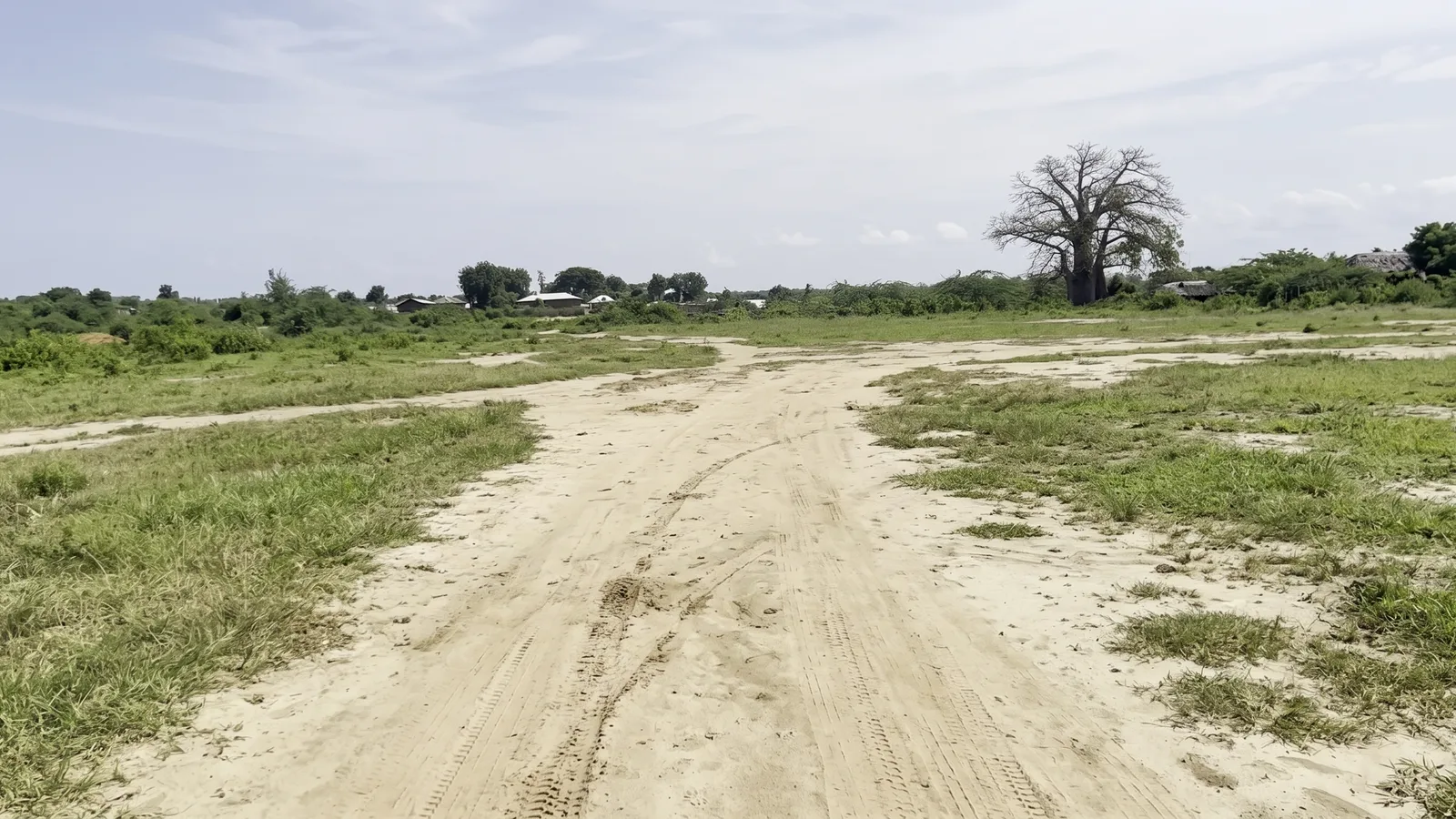 Grassy and sandy plot terrain beneath a broad sky at Mambrui 234 near Sabaki
