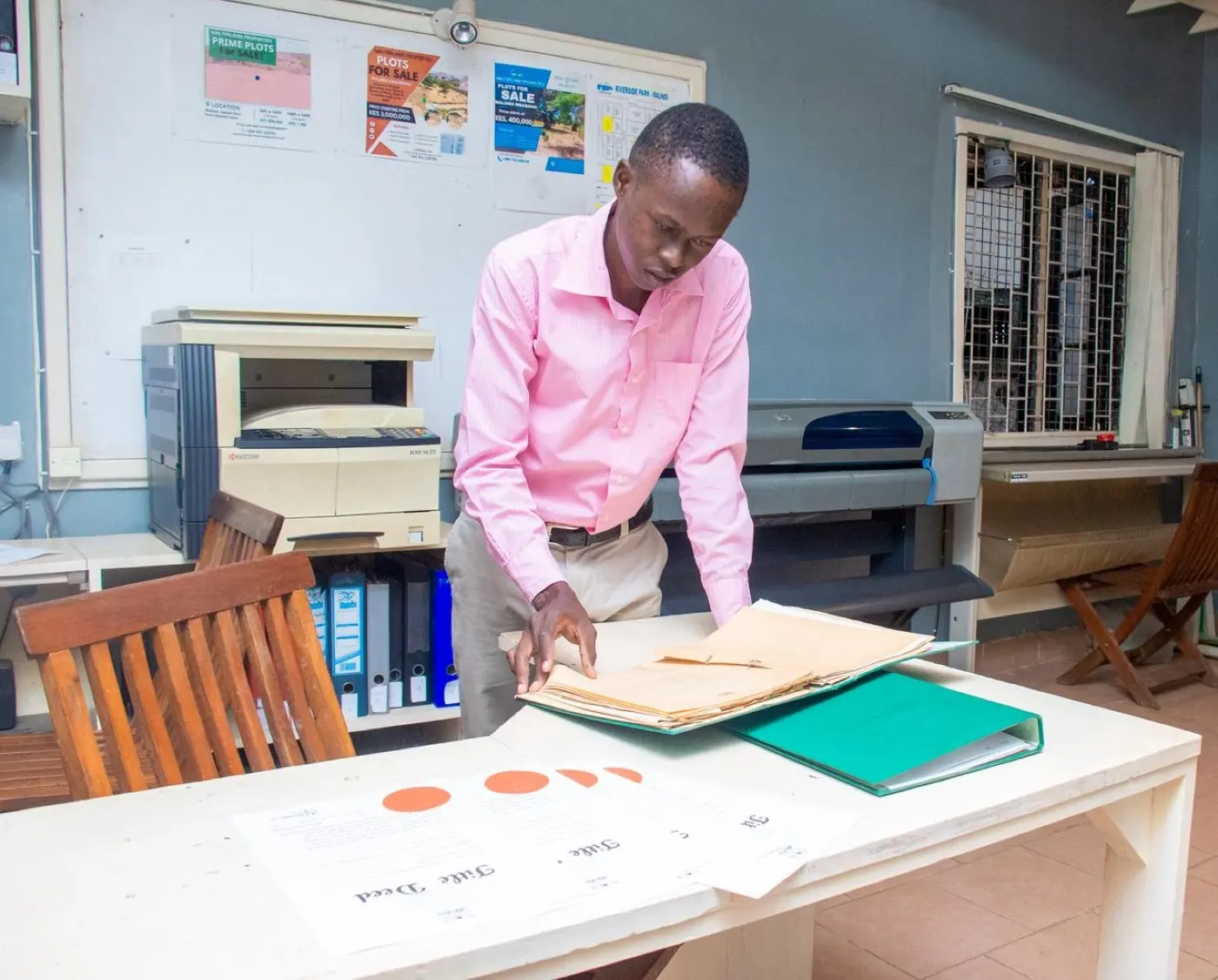 Walterland surveyor reviewing land title deed records at the Malindi office